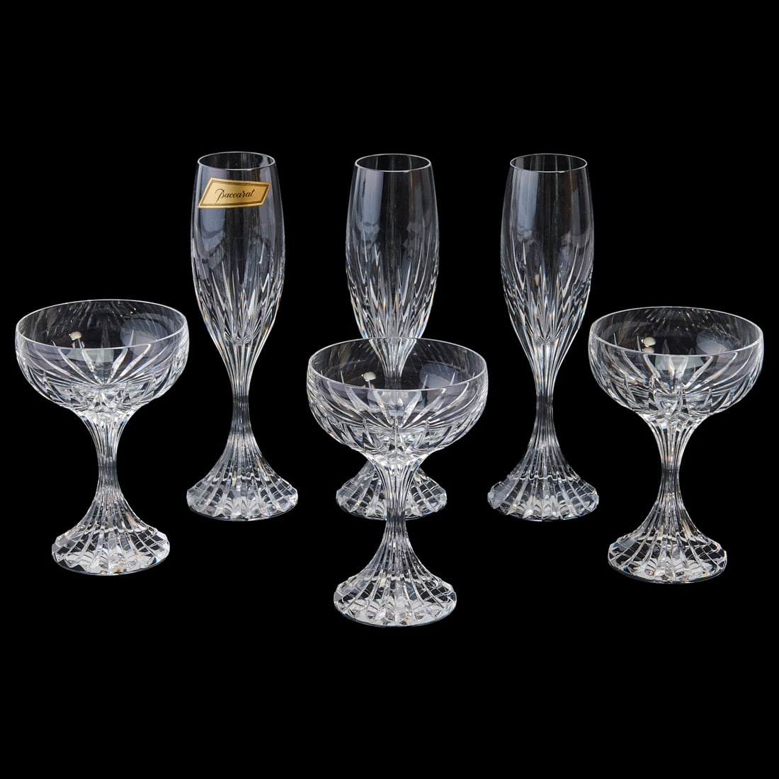 Baccarat Crystal Massena Champagne Stems: Baccarat Crystal Massena Champagne Stems. Comprising 12 champagne flutes and 12 coupes, in a flared facet cut design. Each base underside with engraved Baccarat and pictorial mark. [24 items, total].{