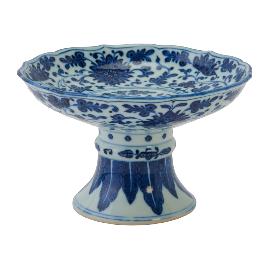 A Chinese Blue and White Lotus-Scroll Stem Dish, Xuande mark: An 18th-century Chinese blue and white lotus-scroll stem dish, Xuande markThe shallow dish molded with a bracket-lobed rim and raised on a tall, spreading hollow foot. The interior is painted in under