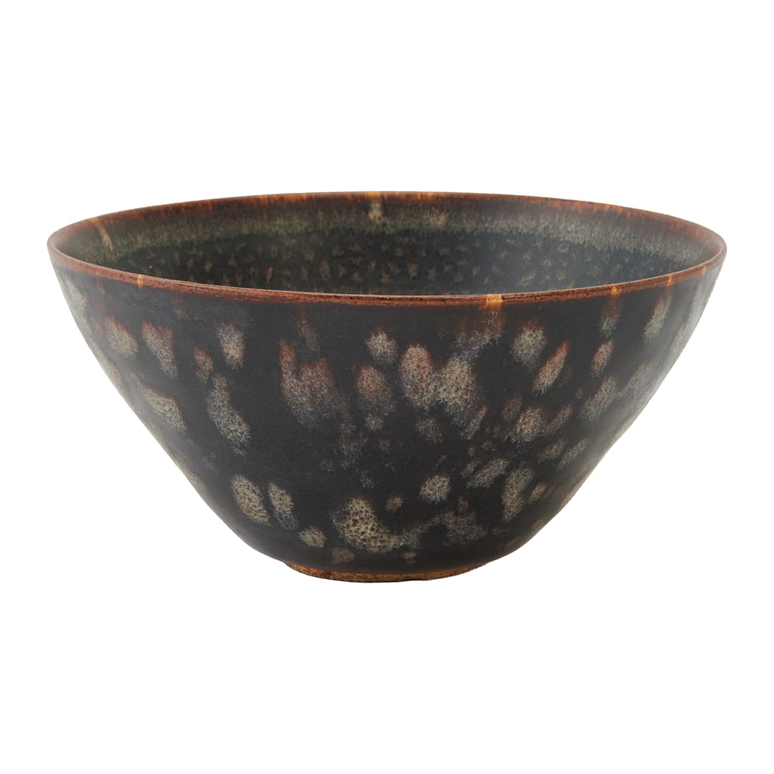 A Chinese Jizhou-type Black-glazed Bowl: The bowl has rounded sides rising from a short circular foot to a plain rim. It is covered inside and out with a lustrous dark brown-black glaze. The interior is decorated with repeated paper-cut flor