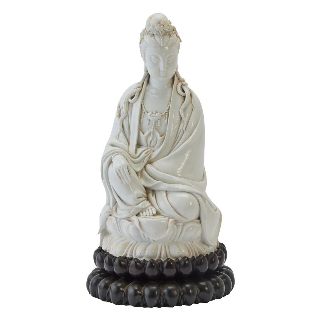 Qing Dynasty Duhua Guanyin Porcelain Figure: This is a late Qing Dynasty Chinese Dehua porcelain figure of Guanyin with wood stand. The finely modeled figure shown seated upon an integral two-tiered lotus throne, wearing voluminous robes and