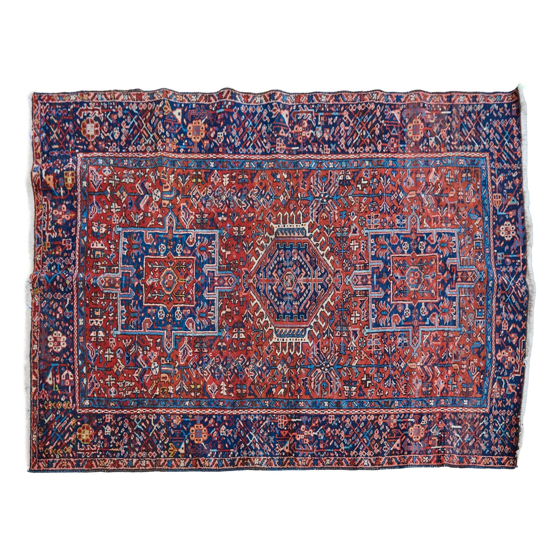 Persian Heriz Wool and Cotton Rug: Persian Heriz Wool and Cotton Rug, red field woven with three medallions of varying shapes, woven with blue primary border and slender guard band border, all with dense geometric and stylized foliate 