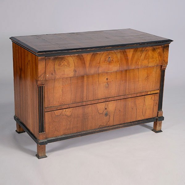 Biedermeier Walnut Commode: Biedermeier Walnut Commode. The outset top with an ebonized molded edge, over three long drawers, the lower two drawers adorsed by ebonized fluted pilaster stiles, raised on block feet cushioned on sq