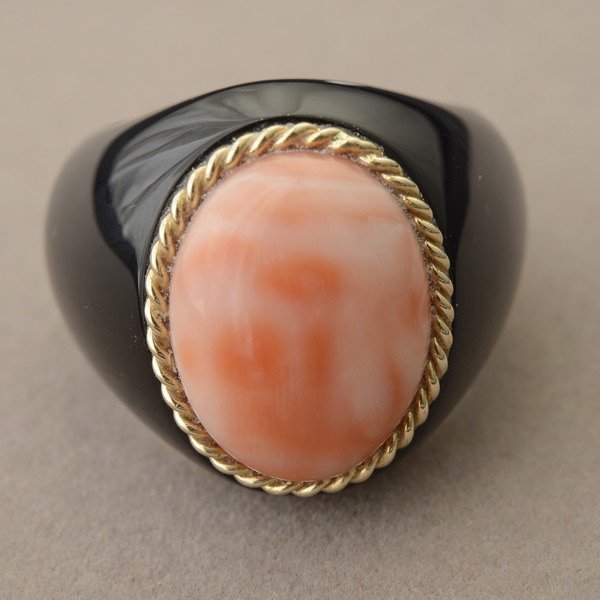 *CORAL, BLACK ONYX, 14K YELLOW GOLD RING.: *CORAL, BLACK ONYX, 14K YELLOW GOLD RING. Centering one coral cabochon measuring approximately 16 x 12 mm, accented by a 14k yellow gold twisted wire bezel and set into a carved black onyx mounting. S