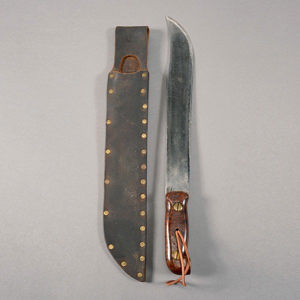 Unmarked Machete with Hardwood Handle: Unmarked Machete with Hardwood Handle and Leather Scabbard 13-inch clipped point blade, with varnished walnut grip panels. Overall length, 18-inches. Leather scabbard with brass rivets. Very good. Pat