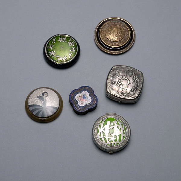 Five Art Deco Compacts and an Enameled Box: Five Art Deco Compacts: Including a German silver example with courting couple {diameter 2 inches}; one marked Djer Kiss; one with Egyptian motif {cracked mirror}; one with lady and fan; and one with