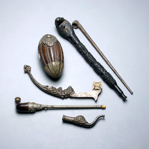 Six Asian Opium Pipes: Six Asian Opium Pipes: the first, a Malaysian totem pole wood pipe; a white metal Indian pipe mouthpiece cast in the form of elephant head and trunk; a Tibetan melon form silver carved wood bowl and t