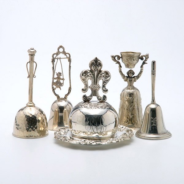 Lot of Five Sterling Bells: Lot of Four Silver Bells: three sterling, including one by Mauser with fleur-de-lis handle; the second by Walker and Hall; a third with English hallmarks; the fourth, a German girl on the swing plated