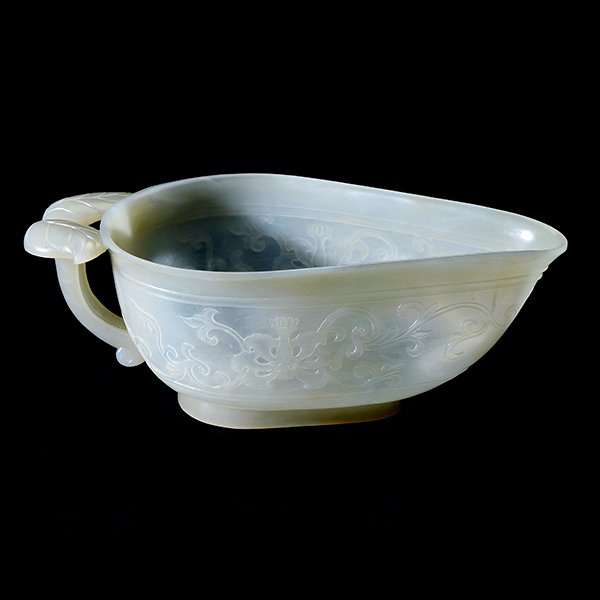 A Mughal-Style Jade Wine Vessel, Republic Period: A Mughal-Style Jade Wine Vessel, The leaf-shaped vessel of deep form, carved with a continuous low relief floral meander encircling the body, the branch-form handle with displaying two curling leaves,