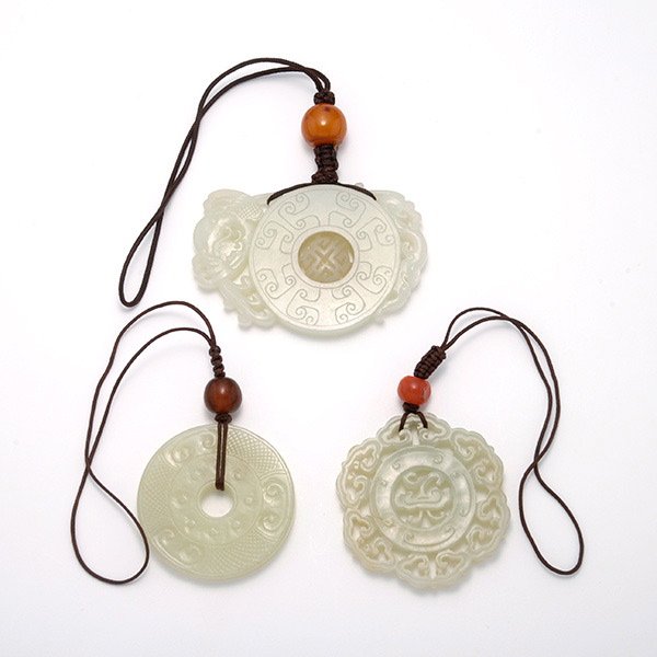 Three Jade Carvings: Three Jade Carvings, Comprising a floriform reticulated pendant, a circular pendant with a central movable shou character and carved with a phoenix and two bats to opposite ends, and a bi disk with in