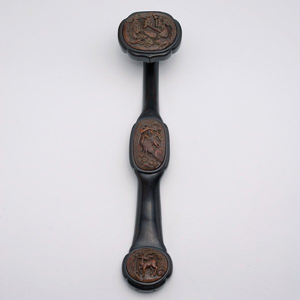 A Zitan Ruyi Scepter: A Zitan Ruyi Scepter, The gently curving zitan handle inset with ovoid bamboo plaques, the head carved with a gathering of sages, and the handle with cranes and a deer beneath leafy trees. Length: 15 