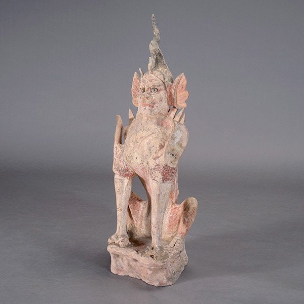 A Painted Pottery of an Earth Spirit, Tang Dynasty: A Large Painted Pottery of an Earth Spirit, Potted with leonine head centered by several horns, hoofed feet, and flame-like projections rising from the back, shown seated on its haunches. Tang Dynasty