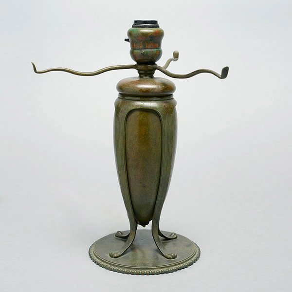 Tiffany Studios Table Lamp Base.: Tiffany Studios Table Lamp Base. The bronze base, finished in brown patina, is fitted with a three arm support for a 12 inch shade. The central urn shaped body is held by 4 ribs terminating in a paw f