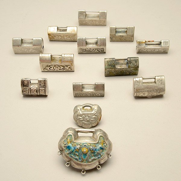 A Group of Thirteen White Metal Locks: A Group of Thirteen White Metal Locks, of various shapes and sizes, decorated with either flowers or beasts reversed by inscriptions, lacking keys {Widest: 2 inches (5.1 cm)} [Dents, abrasions, discol