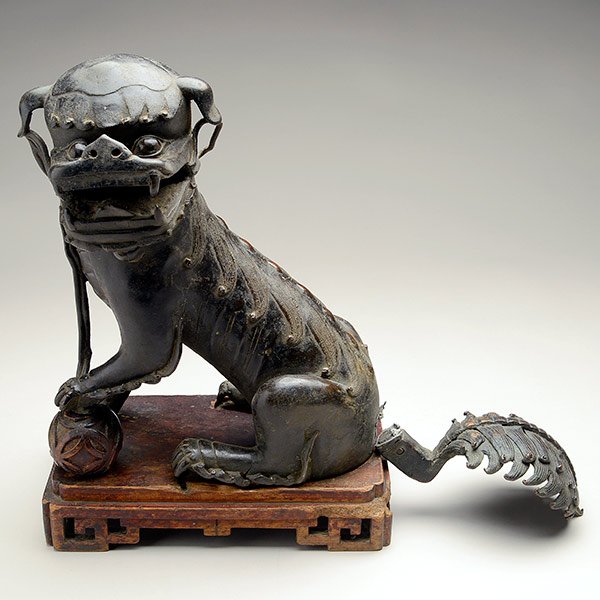A Bronze Buddhist Lion Censer, Ming Dynasty: A Bronze Buddhist Lion Censer The beast seated with its left paw raised on a brocade ball, its scrolling tail flicked upwards, the head detaches forming the cover for the hollow body interior, with fi
