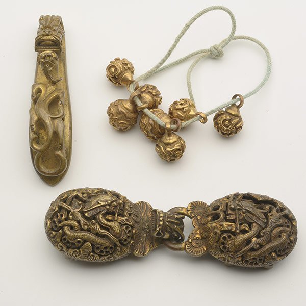 A Group of Gilt-Bronze Accessories, Qing Dynasty: A Group of Gilt-Bronze Accessories Comprising a twin-sectioned belt buckle, a dragon-form belt hook and seven buttons with floral designs. Qing Dynasty Longest: 4 inches (10.2 cm) [Overall wear]