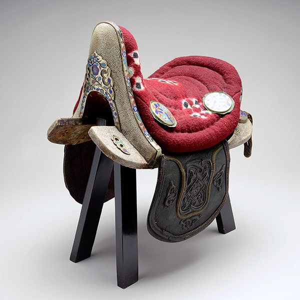 A Chinese Leather and Shagreen Saddle, 19th Century: A Chinese Leather and Shagreen Saddle With brass mounts decorated with flowers in cloisonnÈ enamel, attached to a wood display stand. 19th Century Length: 17 inches (43.2 cm) approximately [Overall w