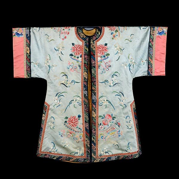 An Embroidered Lady's Informal Coat, Late Qing Dynasty: An Embroidered Lady's Informal Coat The pale sky blue ground worked in satin stitch and Peking knot with sprays of white orchids, pink peonies, chrysanthemums and peaches displayed in baskets, finishe