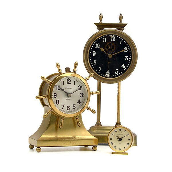 Three Gilt Brass Clocks: Three Gilt Brass Clocks: Comprising a LeCoultre alarm clock, a Waterbury Ship's wheel clock, and a French slide clock, marked 1689 {Height of French slide clock 10 inches}