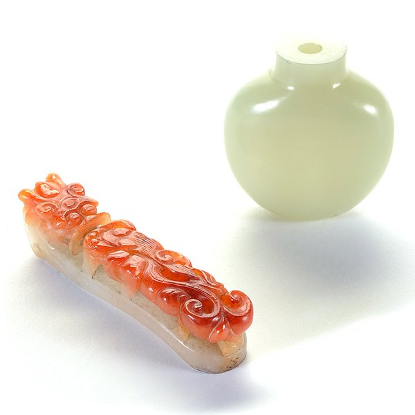 Two Jade Carvings, Late Qing Dynasty: Two Jade Carvings The first is a white nephrite snuff bottle of rounded, spade-shape raised on a slightly concave foot with a slightly waisted neck; the second is a russet jadeite dragon-form belt hoo