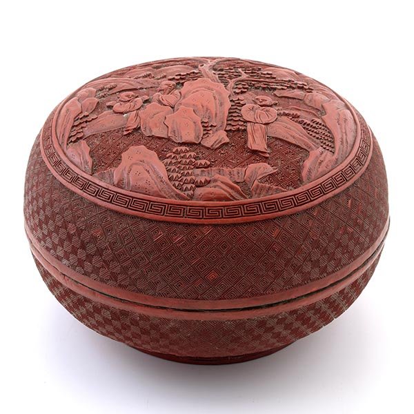 A Cinnabar Lacquer Lidded Box, 19th Century: A Cinnabar Lacquer Lidded Box The circular lid carved with a bearded scholar and two boys in a rock work and pine strewn mountainous landscape. 19th Century Diameter: 7 1/2 inches (19 cm) [Overall wea