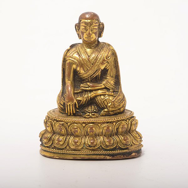 A Gilt-Bronze Figure of a Lama: A Gilt-Bronze Figure of a Lama With his right hand in bhumisparsamudra, covered in voluminous robes elaborately incised with a foliate pattern, the base sealed and incised with a double-vajra. Height:
