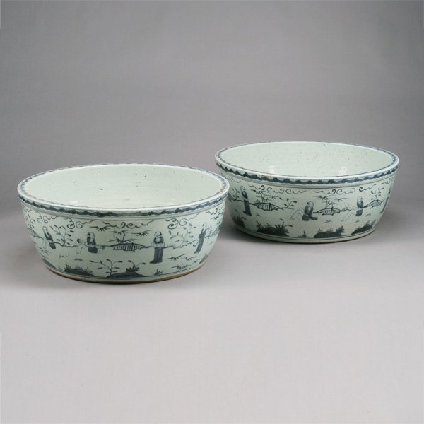 A Pair of Underglaze Blue Basins: A Pair of Underglaze Blue Basins Each shallow bowl continuously decorated with female musicians in a stylized landscape with Buddhist symbols. {Height: 8 1/2 inches (21.6 cm) each; Diameter: 22 1/2 in