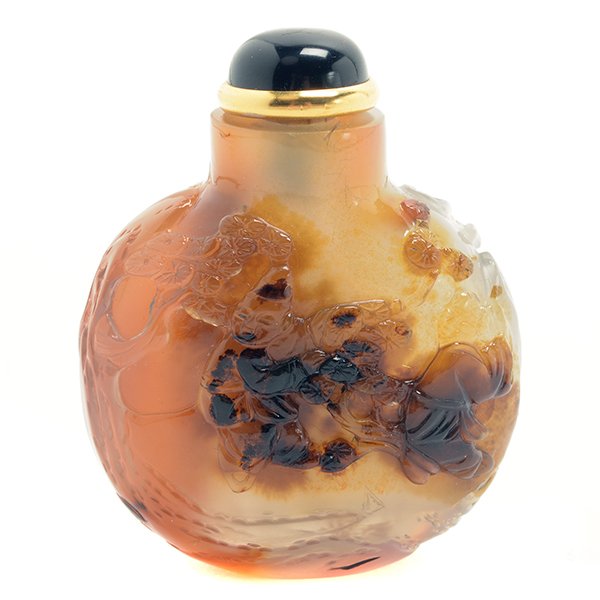 A Small Suzhou School Agate Snuff Bottle: A Small Suzhou School Agate Snuff Bottle Of flattened form with slightly concave lip, finely carved through the darker brown area of the stone with two boys at play in a garden with pine trees. Height