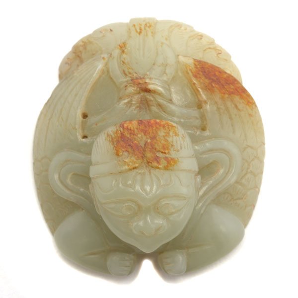 A Russet Jade 'Mythical Creature' Plaque: A Russet Jade 'Mythical Creature' Plaque The personified avian form designed with a human face terminating in a pointed beak, shown holding a billowing ribbon upon its shoulders above a pair of wings