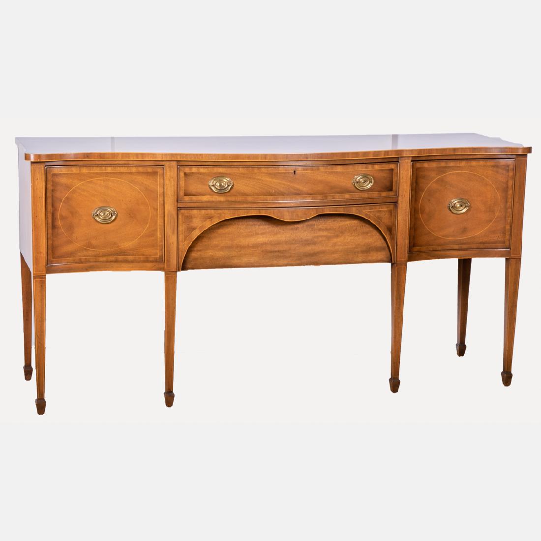 A Kittinger Georgian Style Mahogany Sideboard, 20th: A Kittinger Georgian Style Mahogany Sideboard, 20th Century, Having a rectangular top with serpentine front above two drawers flanked by doors and raised on squared, tapered legs. H: 39 W: 79 D: 23 in