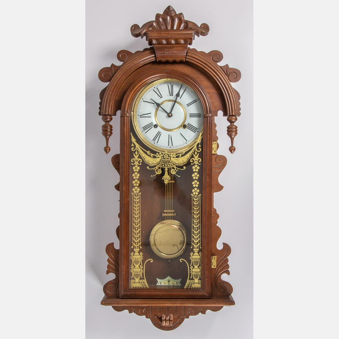 A German Carved Walnut Eight Day Hanging Wall Clock,: A German Carved Walnut Eight Day Hanging Wall Clock, 20th Century, Possibly by the Hamburg-American Clock Co., not in working order. H: 32 W: 16 D: 5 in.