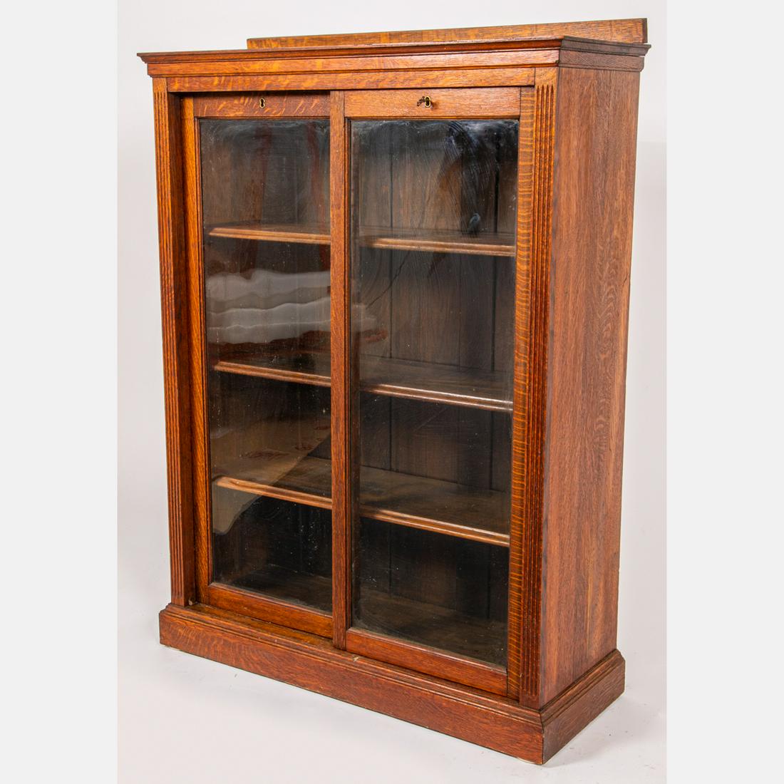 American Oak and Glass Two Door Sliding Book Case: An American Oak and Glass Two Door Sliding Book Case, Early 20th Century, With original key. H: 51 W: 36 1/4 D: 14 in. The absence of a condition statement does not imply that the lot is in perfect co