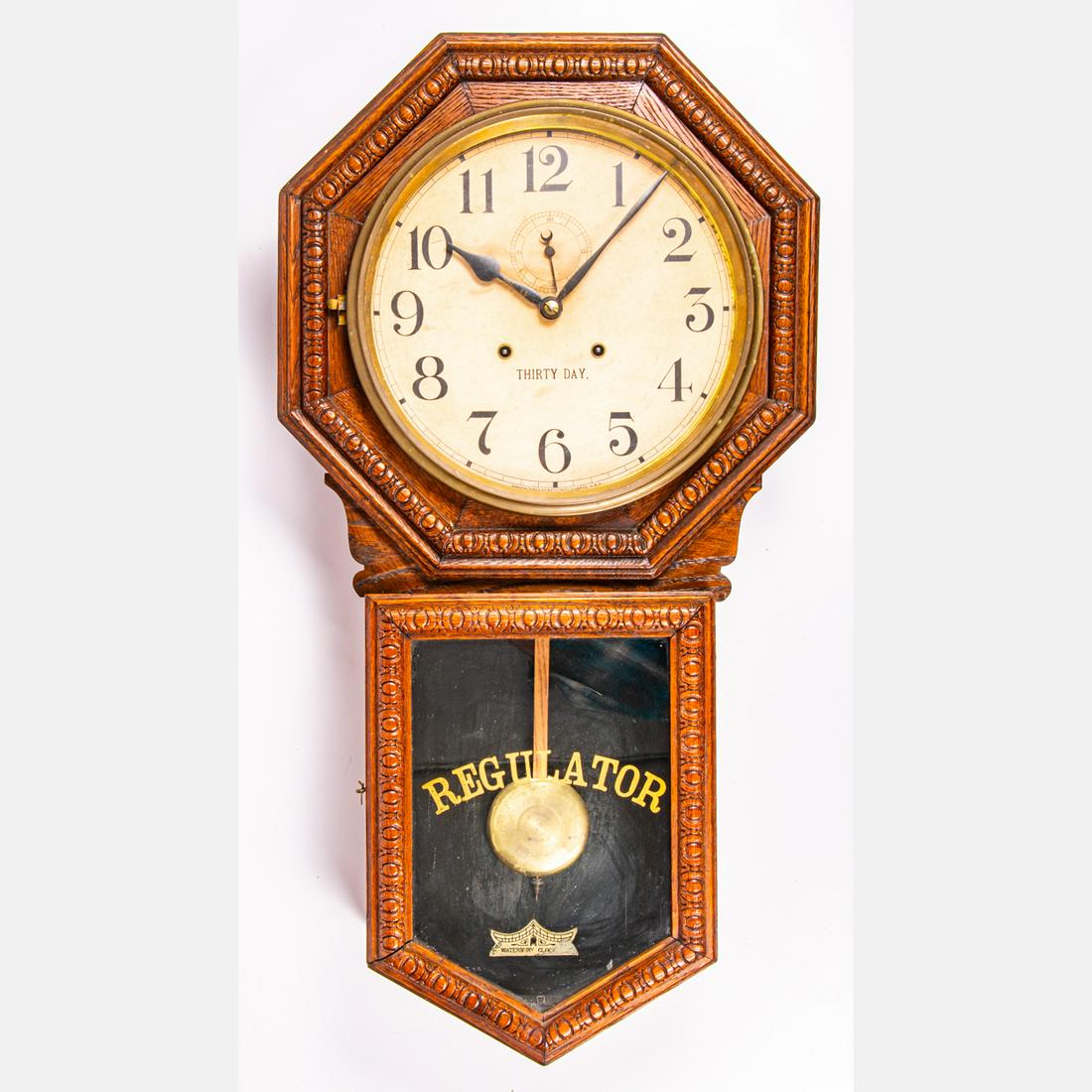 Waterbury Thirty Day Regulator Clock: A Waterbury Thirty Day Regulator Clock, 19th Century, In a pressed oak case. H: 33 W: 17 1/2 D: 5 1/2 in. The absence of a condition statement does not imply that the lot is in perfect condition or co