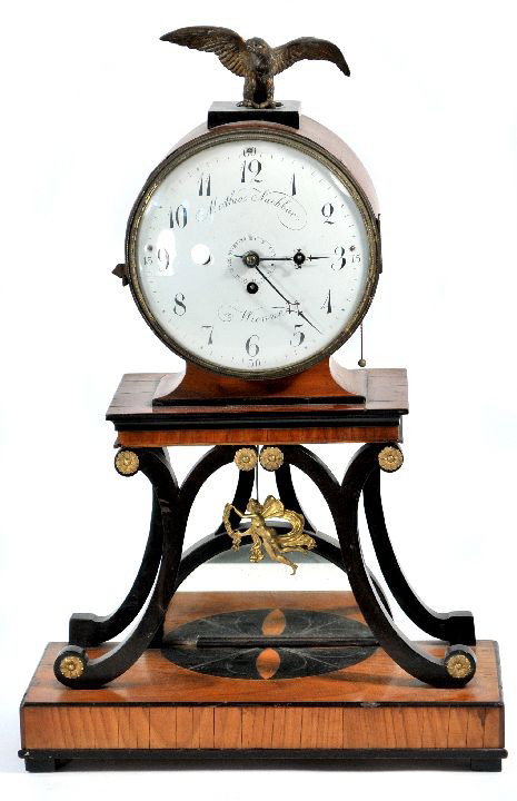 A Mathias Nachbar Biedermeien Mahogany and Gilt Br: A Mathias Nachbar Biedermeien Mahogany and Gilt Brass Clock, 19th Century, Dial signed 'Mathias Nachbar a Wienne', having an eagle form finial above an enamel face raised on scrolling supports with fi