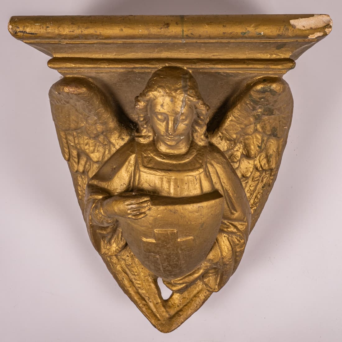 A Cast Plaster Angel Form Bracket Shelf: A Cast Plaster Angel Form Bracket Shelf, 20th Century, Painted gold. H: 16 1/2 W: 15 3/8 D: 11 1/4 in. From the Estate of Douglas W. Lucak The absence of a condition statement does not imply that the