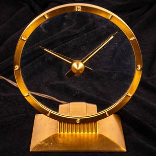 MCM Jefferson Golden Hour Electric Mystery Clock: MCM Jefferson Golden Hour Electric Mystery Clock, 20th Century, 6 1/2 inch glass dial with brass bezel and stand. H: 9 W: 7 1/2 in.