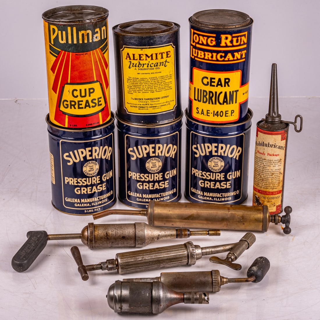 Automotive Lubrication And Greasing Items: Collection Of Automotive Lubrication And Greasing Items, Mid 20th Century, Three cans of Superior Pressure Gun Grease, empty. One can of Pullman Cup Grease, empty. One can of Long Run Lubricant, empty