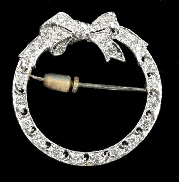 An 18kt. White Gold and Diamond Melee Circular Rib: An 18kt. White Gold and Diamond Melee Circular Ribbon Form Brooch. Total approximate weight: 3.5 dwt.