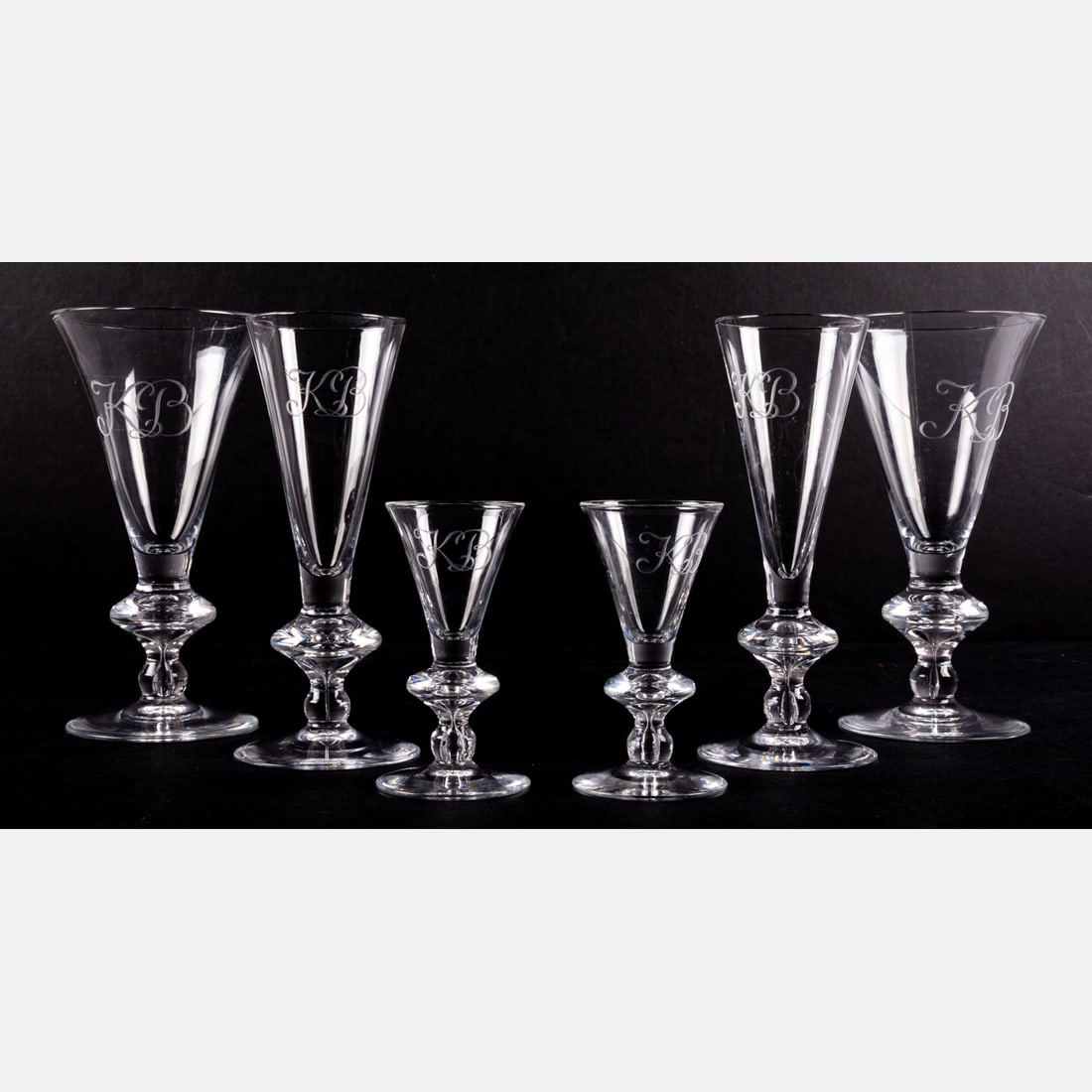 Six Steuben Crystal Glasses: Six Steuben Crystal Glasses. Comprising Two water goblets (7 1/4 inches tall,) two wine glasses (7 inches tall) and two cordial glasses (4 1/8 inches tall.) Each engraved with script monogram KB. Wate