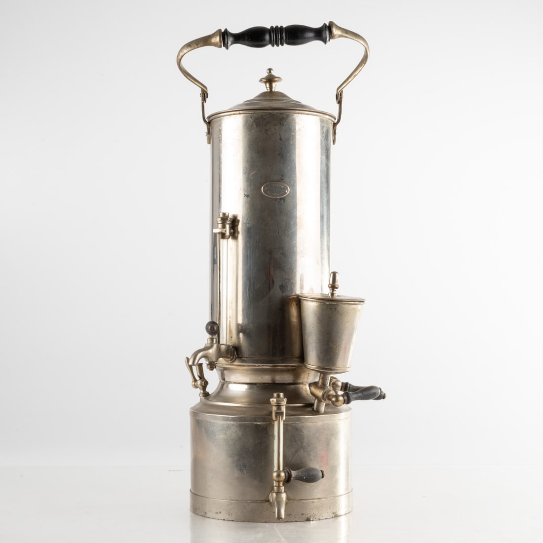 An Antique Commercial Coffee Maker: An Antique Commercial Coffee Maker, 20th Century, Manufactured by Adolfo Marquet, Madrid, Nickel Plated Brass and Metal, with black wood handles, H: 19 W: 10 D: 7 in. From the Estate of John A. Davids