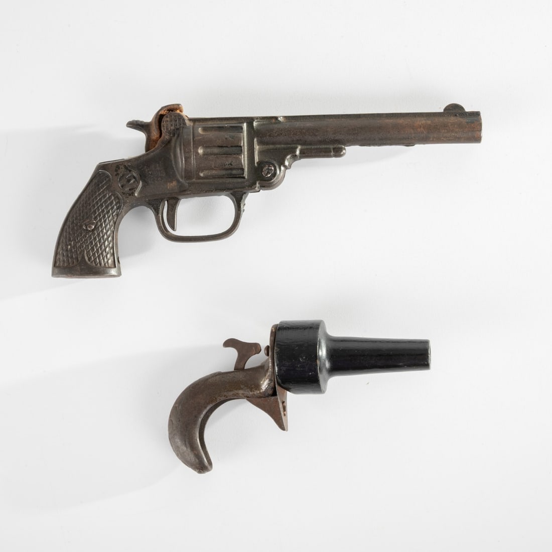1923 Kenton SW Indian Cast Iron Toy Gun: A 1923 Kenton SW Indian Cast Iron Single Shot Cap Revolver Toy Gun, Together with an Antique Cast Iron and Wood Clicker Pistol. Largest dimensions: H: 3 1/2 x L: 8 1/4 x D: 1 1/4 H: 3 1/2 W: 8 1/4 D: