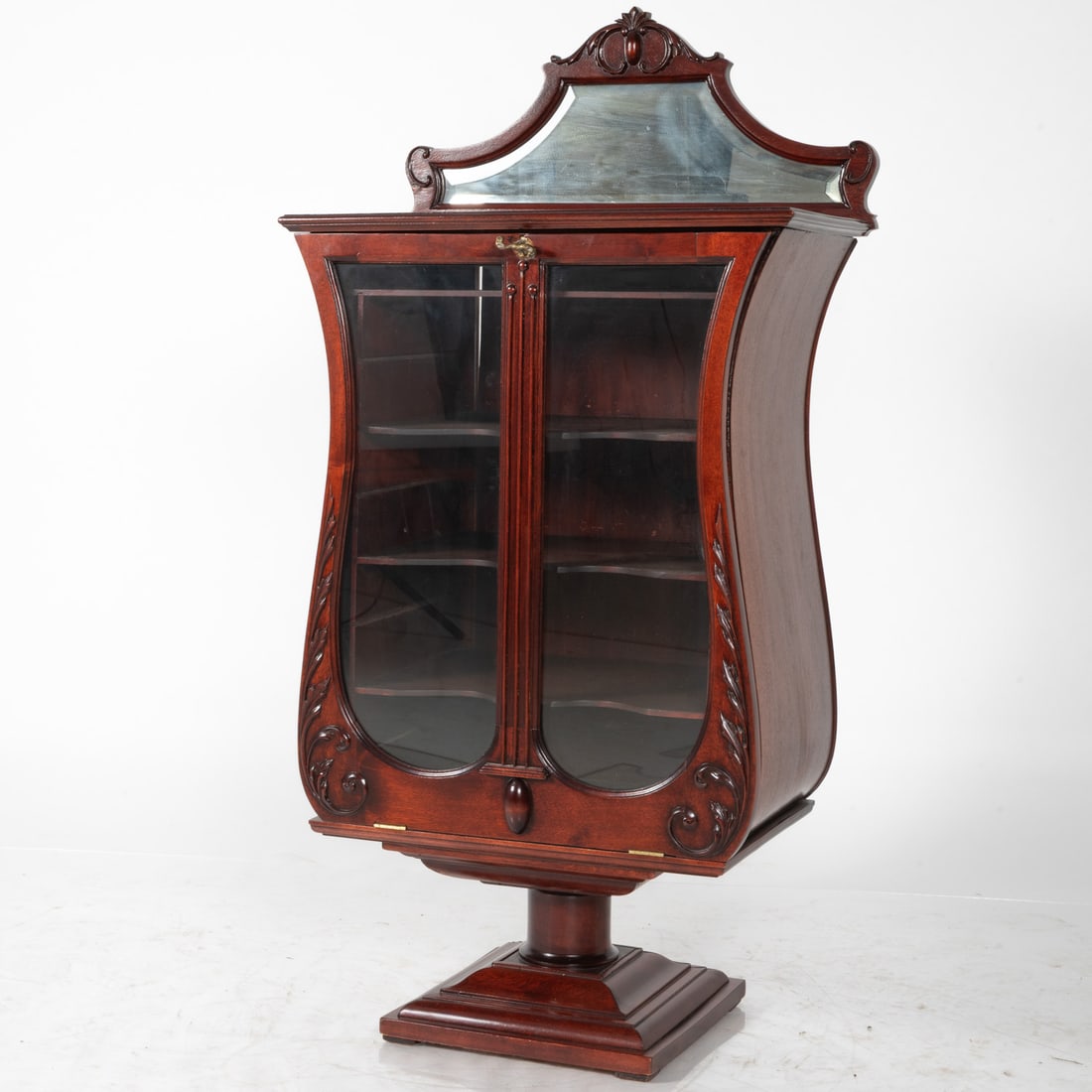 American Harp Form Music Cabinet: An American Victorian Mahogany and Glass Sheet Music Cabinet, 19th Century. Harp form cabinet with mirrored back. H: 46 W: 23 D: 14 in.