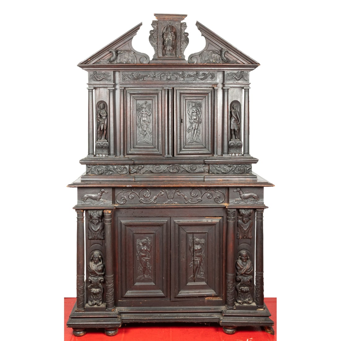 A French Renaissance Revival Oak Cabinet A Deux Corps: A French Renaissance Revival Oak Cabinet A Deux Corps, 19th Century, Heavily carved with figures, vines, and dogs beneath a broken arch pediment over two upper and lower cabinet doors separated by thr