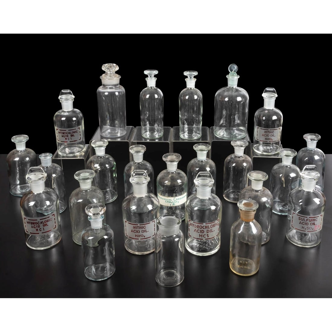 24 Scientific Laboratory Glass Bottles: Twenty Four Scientific Laboratory Glass Bottles, 20th Century, Comprising 6 Pyrex bottles with red chemical labels, nine plain matching; seven with stoppers of various sizes and 2 without stoppers -