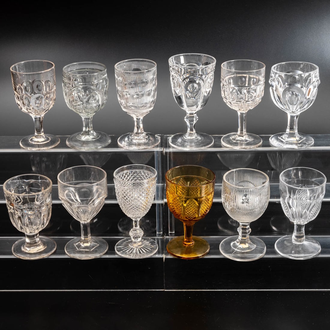 12 EAPG Pressed Glass Goblets: Twelve American Pressed Glass Goblets, 19th/20th Century, Having two, three (tri-mold) or four mold joints,amber and clear glass. Comprising: Bull's Eye, 1850; Block and Thumbprint, 1880s; Diamond Poi