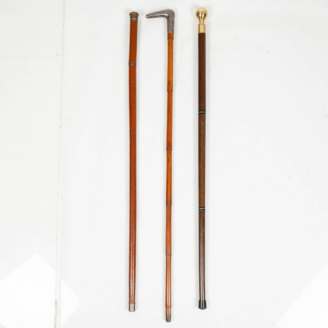 3 Walking Sticks: Three Walking Sticks, 19th/20th Century, Comprising an English sterling silver handle and bamboo cane hallmarked London 1894 by Charles Henry Dumenil; a poison vial and glass filled stick with a