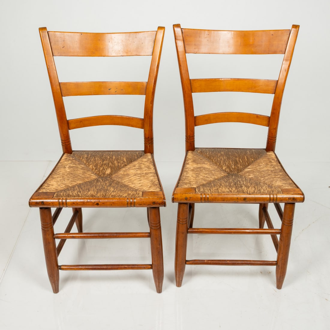 Pair of American Maple and Hickory Ladderback Chairs: A Pair of American Maple and Hickory Ladderback Chairs, 19th Century, Three ladder backs with hickory double stretchers on three sides and rush seats. H: 35 W: 17 D: 15 in. The collection of an Ohio f