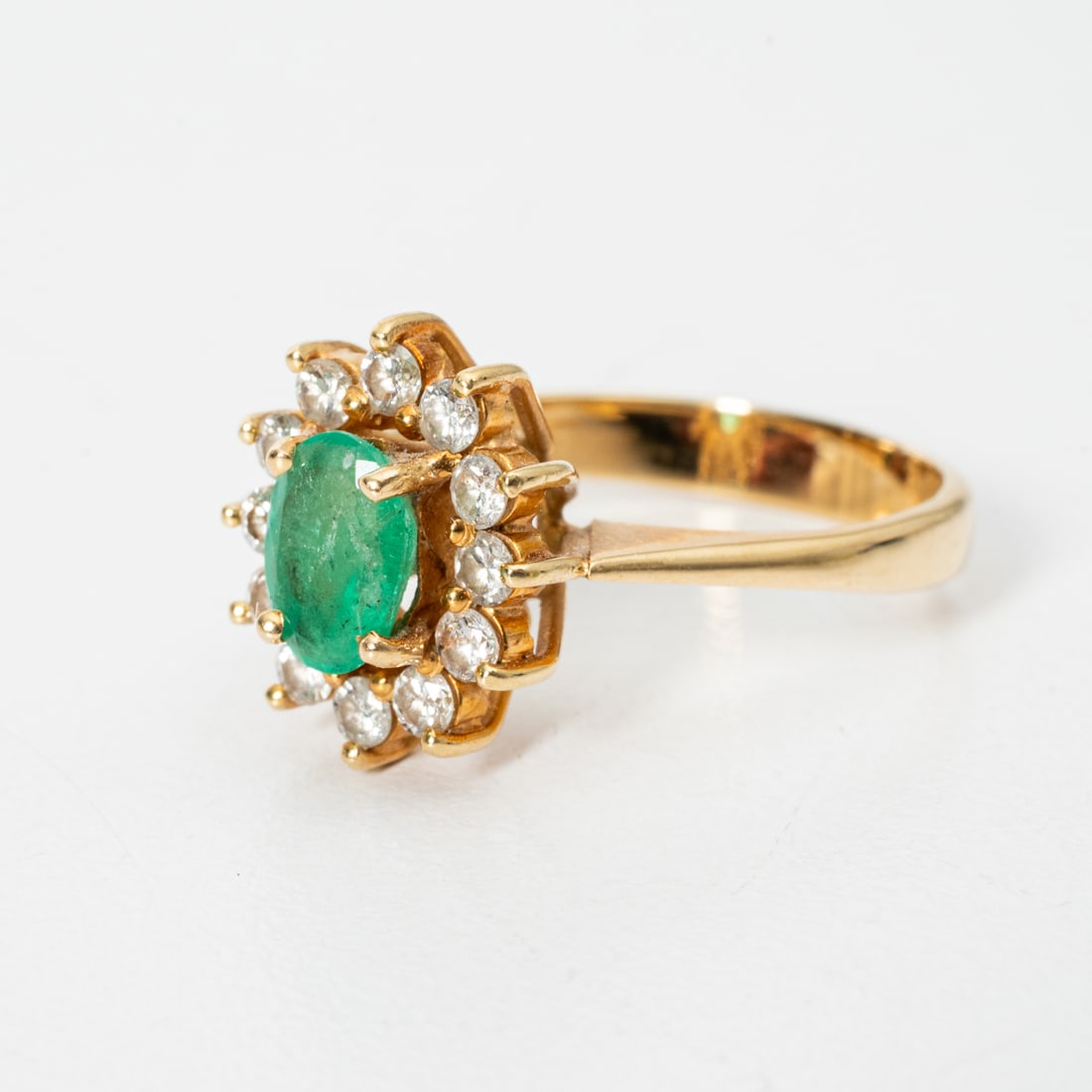 18K Yellow Gold Emerald and Diamond Ring: 18K Yellow Gold Emerald and Diamond Ring, Set with One Oval Cut Natural Emerald, Approximately 0.50 pts, Also set with 12 round brilliant cut diamond melee each approximately 0.05 pts. Unmarked. Gold