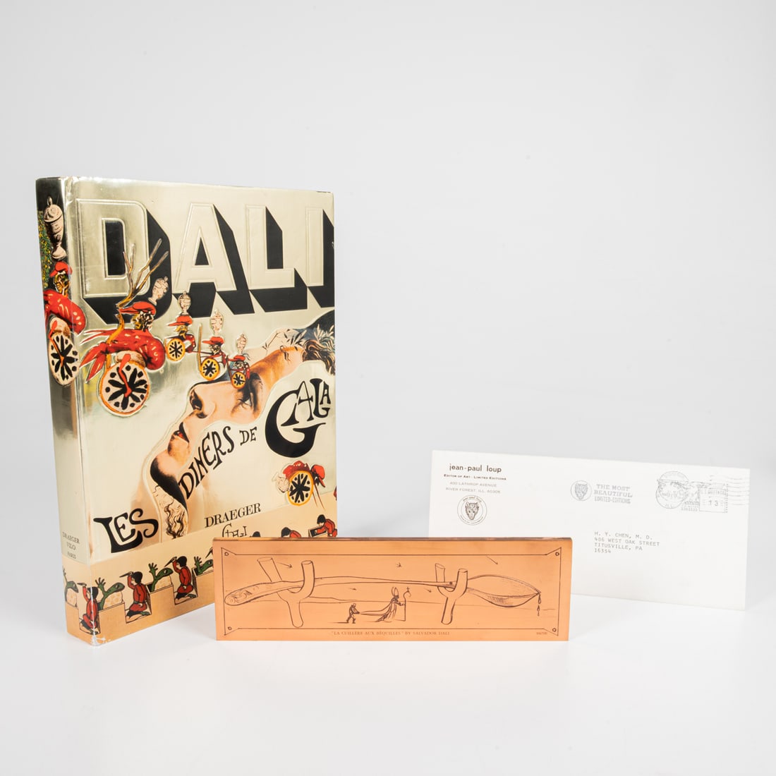 Salvador Dali (Spanish, 1904 - 1989): Salvador Dali (Spanish, 1904 - 1989) Les Diners de Gala Cookbook & Copper Paperweight Cookbook numbered 116/590 Copper paperweight numbered: 104/590 Cookbook with 96 color plates and 136 recipes in a 