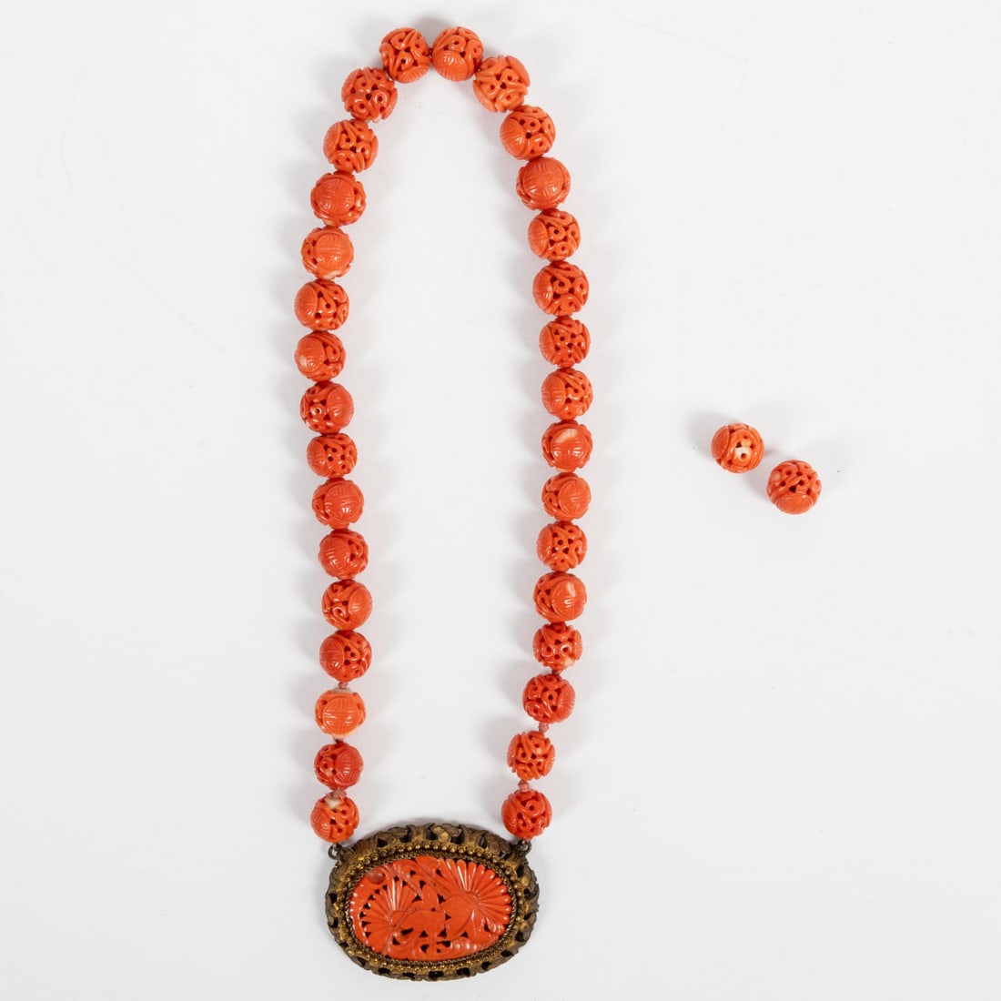 A Chinese Carved Coral Bead Necklace and Pendant: A Chinese Carved Coral Bead Necklace and Pendant, 19th Century, Having pierced carved 10mm pink coral beads each with a pair of Shou medallions, surrounded by scrolling designs, ending in an oval carv