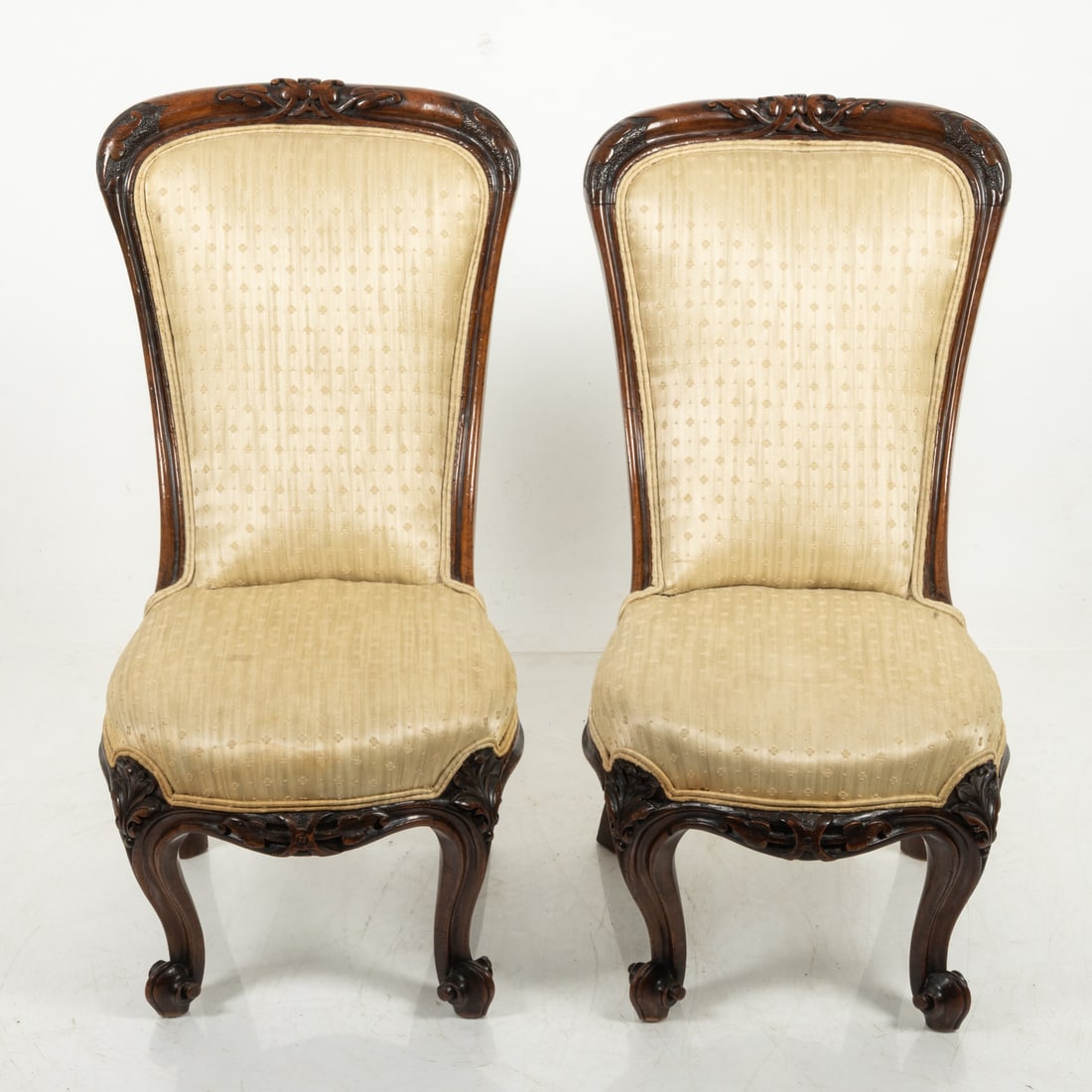 A Pair of American Slipper Chairs: A Pair of American Carved Walnut and Upholstered Slipper Chairs, 19th Century. Chair dim: H: 28 1/4 X W: 16 X D: 21 1/2 in. Seat dim: W: 14 1/2 X D: 13 1/2 in. Seat to floor: 12 1/2 in.